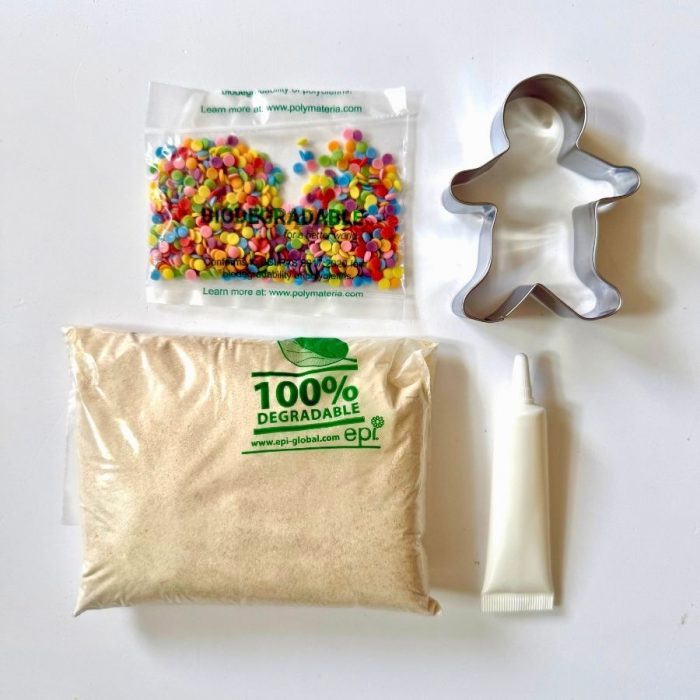Contents of the Katie Bakes Gingerbread pouch, gingerbread man cutter, icing, gingerbread baking mix, cookie cutter and decorations.