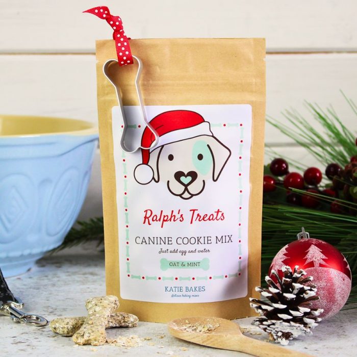 Christmas dog treat baking mix with bone shaped cookie cutter and baked treats in the foreground