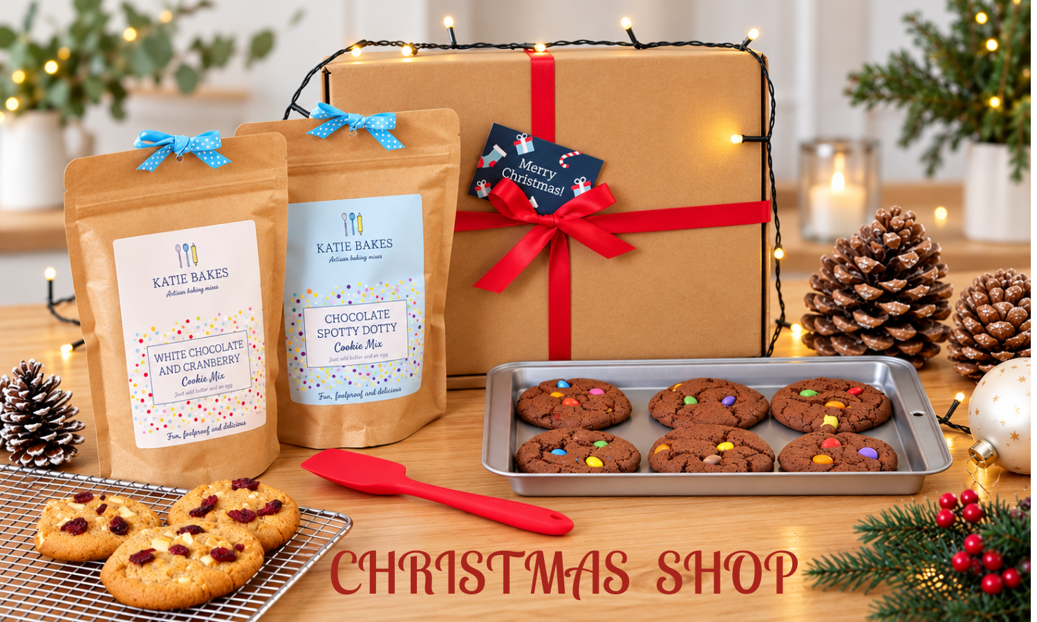 Cookie mix pouches with a gift box and silicone mixing spoon and baked cookies in a Christmas setting.